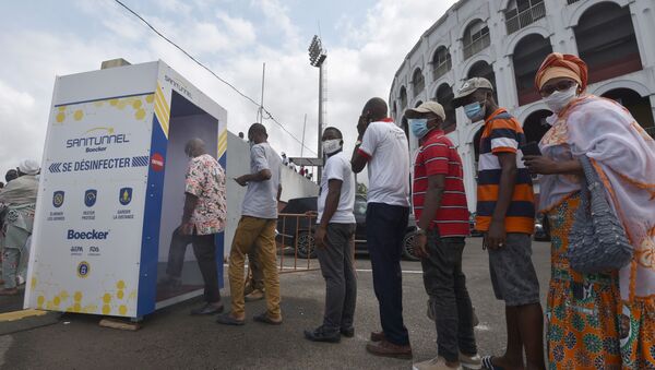 Des supporters RHDP passent dans un tunnel de désinfection avant la cérémonie en hommage à Amadou Gon Cloulibaly à Abidja, le 15 juillet 2020. - Sputnik Afrique