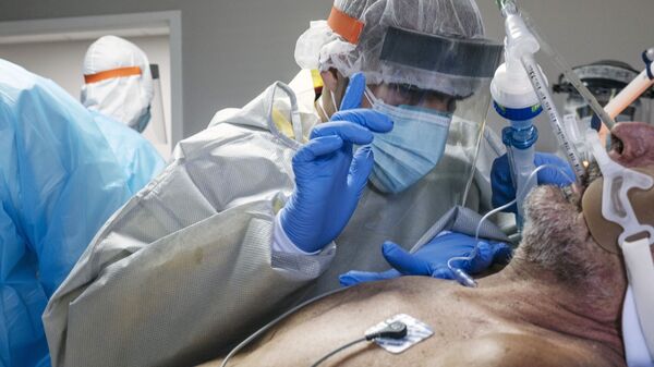 Un médecin examine un patient atteint du Covid-19 dans un hôpital, image d'illustration - Sputnik Afrique