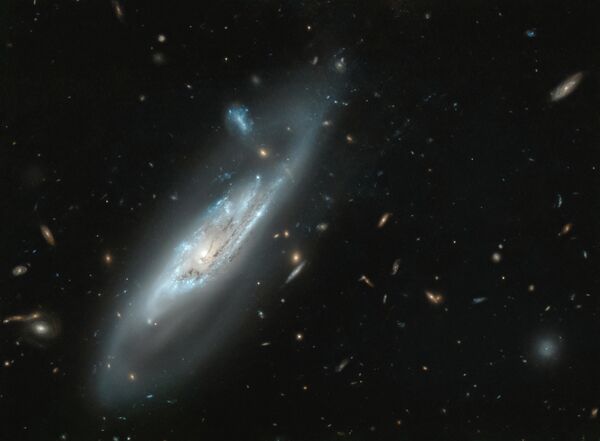 Sur la photo de la galaxie spirale NGC 4848 prise par le télescope Hubble, on peut voir en détail des manches bleu argent émanant du centre. - Sputnik Afrique