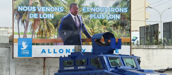 Un véhicule de l'armée togolaise garé devant une affiche électorale du Président Faure Gnassingbé - Sputnik Afrique