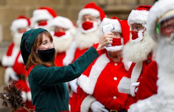 Une jeune femme déguisée en elfe prend la température des visiteurs de l'école de Santa Claus de Londres.  - Sputnik Afrique