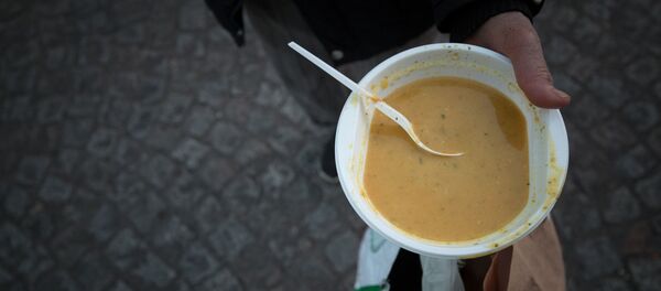 Un individu tient un bol de soupe lors d'une distribution du Secours Populaire Un individu tient un bol de soupe lors d'une distribution du Secours Populaire - Sputnik Afrique