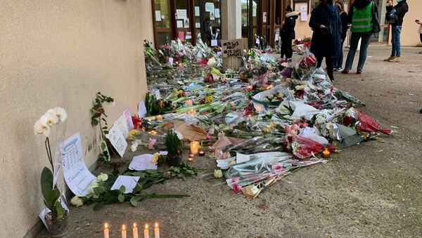 Des enseignants déposent des fleurs devant le collège du Bois d’Aulne à Conflans-Sainte-Honorine en hommage à Samuel Paty, décapité le 16 octobre  - Sputnik Afrique
