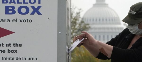 With the U.S. Capitol dome visible, a voter drops a ballot into an early voting drop box, Wednesday, Oct. 28, 2020, at Union Market in Washington - Sputnik Afrique