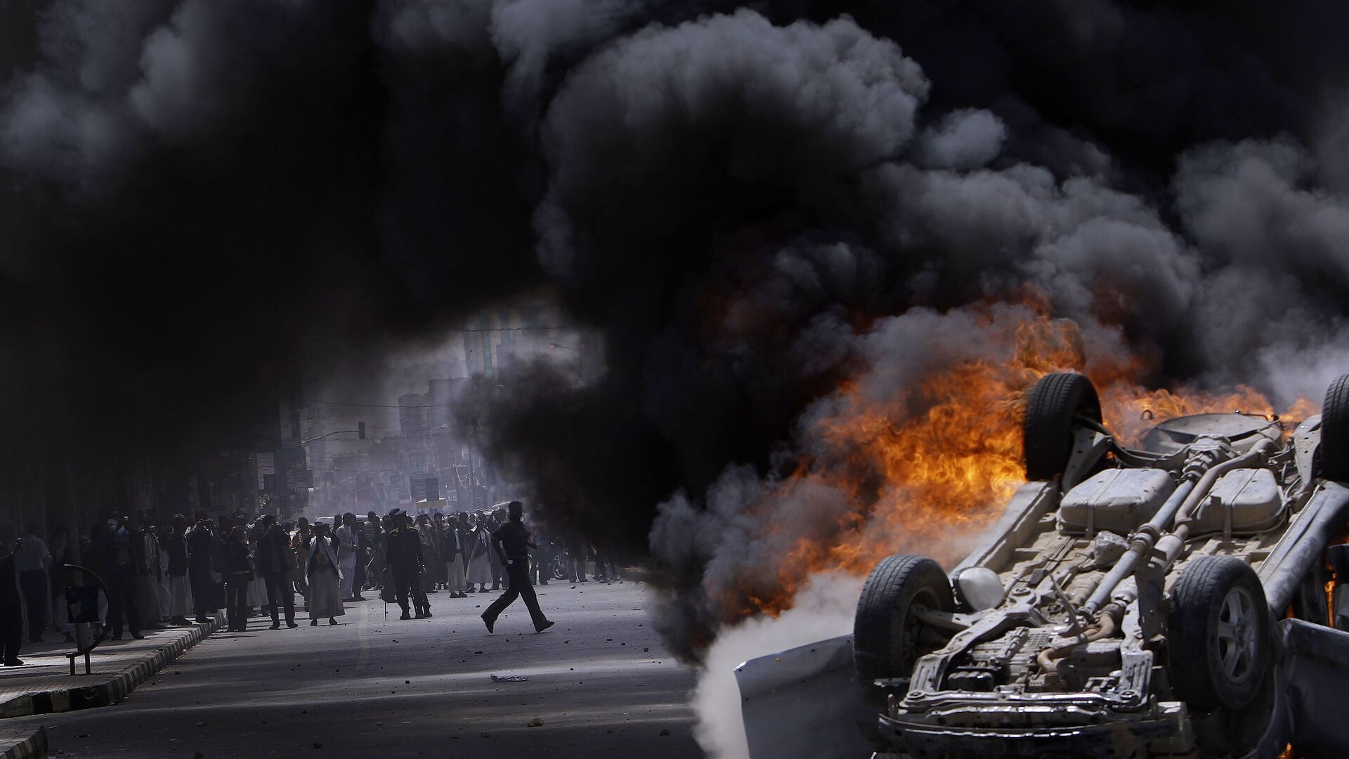 Горящий автомобиль, подожженный антиправительственными демонстрантами во время беспорядков в Сане, Йемен, 2011 год - Sputnik Afrique, 1920, 19.01.2022