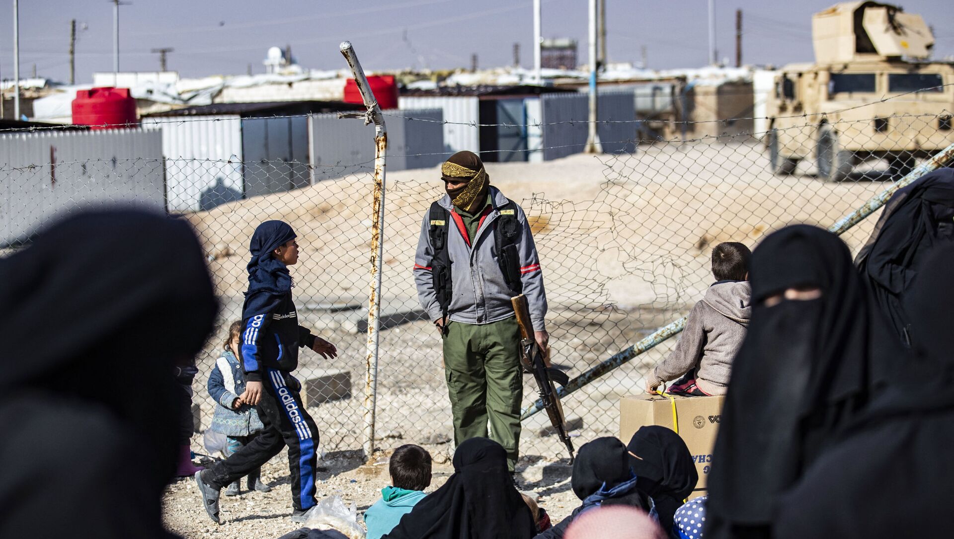Un membre de la sécurité intérieure kurde monte la garde alors que des femmes conduisent des enfants avant leur départ, lors de la libération d'un autre groupe de familles syriennes du camp kurde d'al-Hol, qui détient des parents présumés de combattants du groupe de l'État islamique (IS), dans le gouvernorat de Hasakeh, au nord-est de la Syrie, le 28 janvier 2021.
Delil SOULEIMAN / AFP
 - Sputnik Afrique, 1920, 13.02.2021