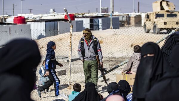 Un membre de la sécurité intérieure kurde monte la garde alors que des femmes conduisent des enfants avant leur départ, lors de la libération d'un autre groupe de familles syriennes du camp kurde d'al-Hol, qui détient des parents présumés de combattants du groupe de l'État islamique (IS), dans le gouvernorat de Hasakeh, au nord-est de la Syrie, le 28 janvier 2021.
Delil SOULEIMAN / AFP
 - Sputnik Afrique