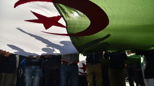 Des manifestants algériens brandissent le drapeau national lors d'une manifestation dans la capitale Alger, le 28 février 2020. - Des manifestations de masse ont éclaté en Algérie il y a un an samedi dernier, en réponse au président Abdelaziz Bouteflika qui a annoncé son intention de briguer un cinquième mandat après 20 ans au pouvoir -- bien qu'il soit affaibli par un accident vasculaire cérébral survenu en 2013. (Photo par RYAD KRAMDI / AFP) - Sputnik Afrique