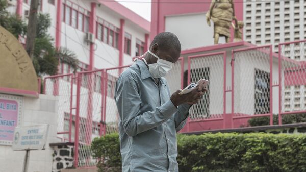 Un homme portant un masque devant l'entrée de l'hôpital de Yaoundé - Sputnik Afrique
