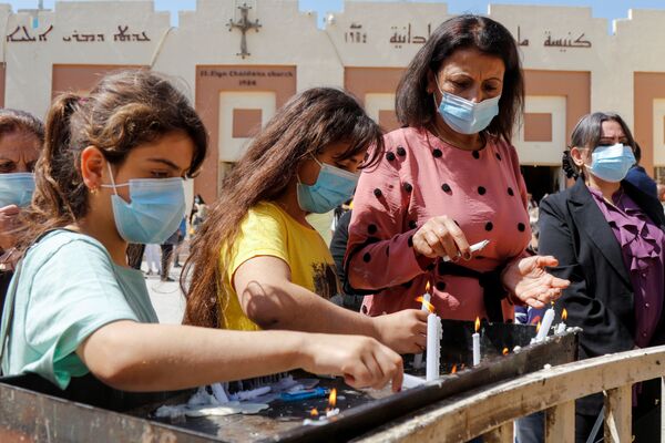Les gens allument des bougies après une messe de Pâques, à l'extérieur de l'église chaldéenne de Saint-Élie, en pleine épidémie de Covid-19, à Bagdad, Irak, le 4 avril 2021. - Sputnik Afrique