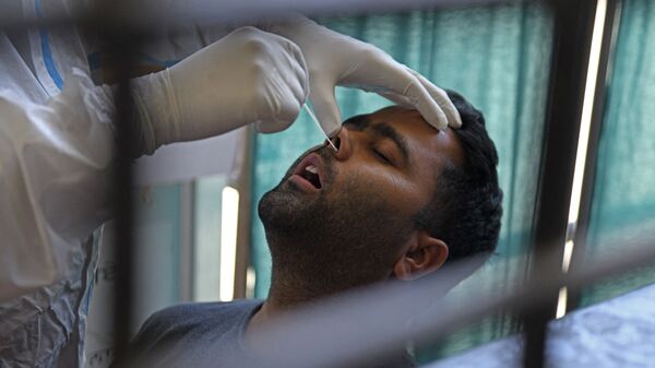 Un agent de santé prélève un échantillon par écouvillonnage nasal sur un homme pour tester le coronavirus Covid-19 à Amritsar en Inde, le 18 avril 2021. - Sputnik Afrique