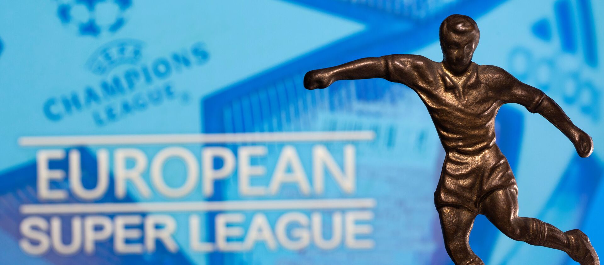 A metal figure of a football player with a ball is seen in front of the words European Super League and the UEFA Champions League logo in this illustration taken April 20, 2021 - Sputnik Afrique, 1920, 21.04.2021