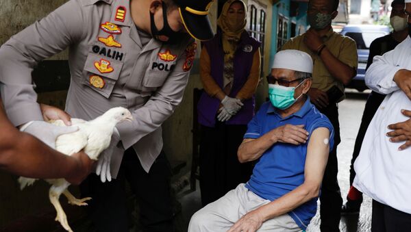 Полиция с курицей во время одаривания вакцинированных в Индонезии  - Sputnik Afrique