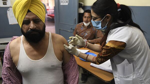 A medical worker inoculates a man with a dose of the Covishield, ChAdOx1 nCoV-19 coronavirus vaccine, at a civil hospital in Ajnala village, about 28 km from Amritsar on April 1, 2021 - Sputnik Afrique