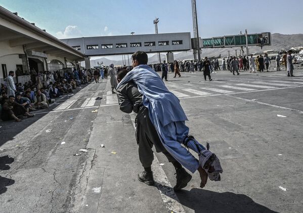 Un volontaire aide un homme blessé à se rendre sur le lieu d'évacuation à l'aéroport international de Kaboul. - Sputnik Afrique