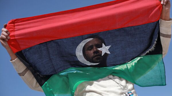 Un habitant de Benghazi avec un drapeau libyen - Sputnik Afrique