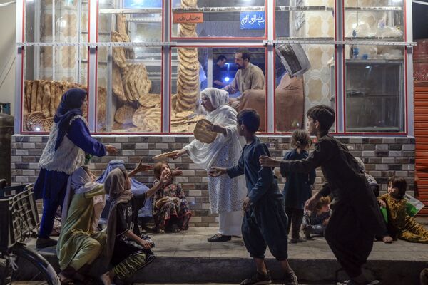 Après l’arrivée au pouvoir des talibans*, l’Afghanistan traverse une crise économique. De nombreux Afghans se sont retrouvés sans emploi. Selon l’Onu, dans les mois à venir, il faut s’attendre à une hausse des prix des denrées alimentaires et à une montée de la pauvreté.Sur la photo: une femme distribue du pain aux enfants devant une boulangerie à Kaboul. - Sputnik Afrique