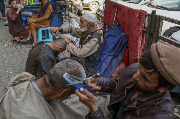 De nombreux Afghans se souviennent encore des événements d’il y a vingt ans et le retour des talibans* leur fait très peur.Sur la photo: des barbiers et leurs clients dans une rue à Kaboul. - Sputnik Afrique