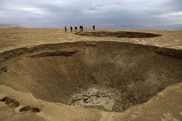 Certains de ces cratères ont une profondeur de plus de 10 mètres. Selon des géologues israéliens, le littoral de la mer Morte est aujourd&#x27;hui parsemé de milliers d&#x27;excavations de ce type.Sur la photo: des touristes sur une saline, située à 20 kilomètres au sud du kibboutz Ein Gedi, qui s&#x27;est formée sur une partie desséchée de la mer Morte. - Sputnik Afrique