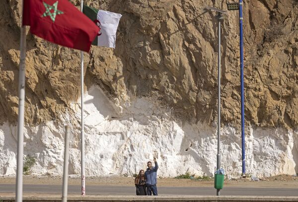 La frontière terrestre entre l’Algérie et le Maroc est fermée depuis 1994 après l’instauration par les autorités marocaines d’un régime de visa pour les Algériens. Il s’agit de la plus longue frontière fermée entre deux pays: elle s’étend sur 1.900 kilomètres.Sur la photo: des Algériens saluent leurs proches du côté marocain de la frontière fermée. - Sputnik Afrique