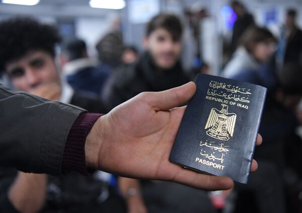 Un migrant irakien qui attend son retour en Irak à l’aéroport de Minsk montre son passeport. - Sputnik Afrique