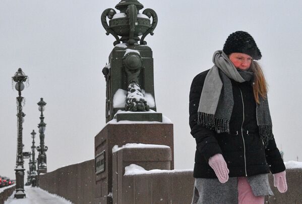 Une femme traverse le pont Troïtski à Saint-Pétersbourg pendant qu’il neige. - Sputnik Afrique