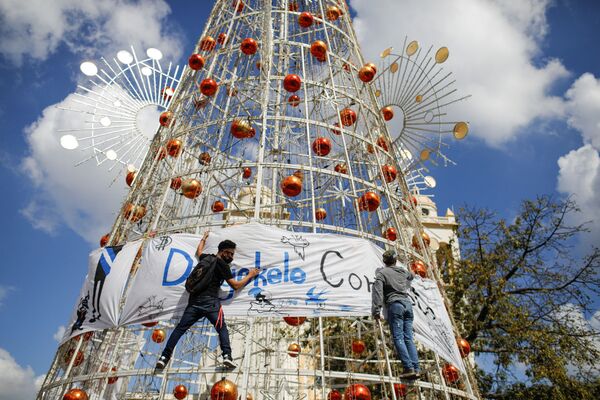 Des militants accrochent une banderole à un sapin de Noël à San Salvador lors d’une manifestation contre la politique du Président du Salvador, Nayib Bukele. - Sputnik Afrique