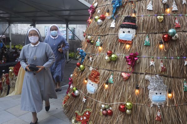 Des religieuses passent devant un arbre de Noël en se rendant à un service de Noël dans une église à Bali, en Indonésie (2020). - Sputnik Afrique