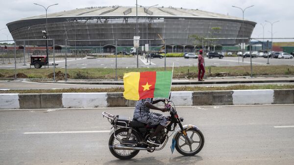 Un supporter camerounais passe devant le stade de Japoma à Douala - Sputnik Afrique
