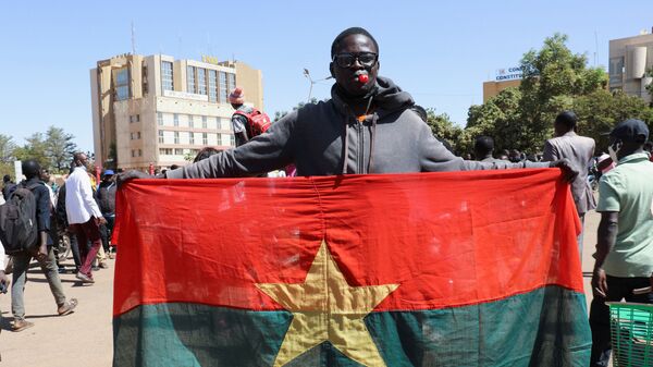 Un sympathisant des militaires brandit un drapeau national à Ouagadougou - Sputnik Afrique