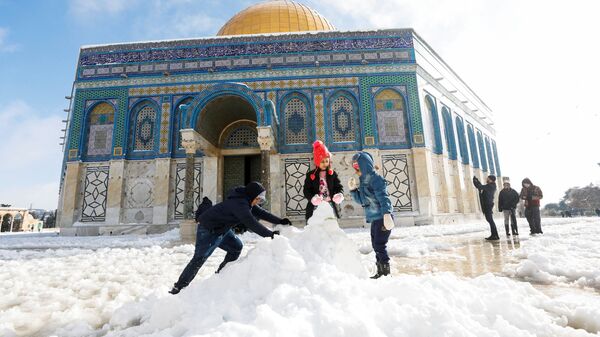 Дети строят снеговика перед мечетью Купол Скалы, расположенной в Старом городе Иерусалима - Sputnik Afrique