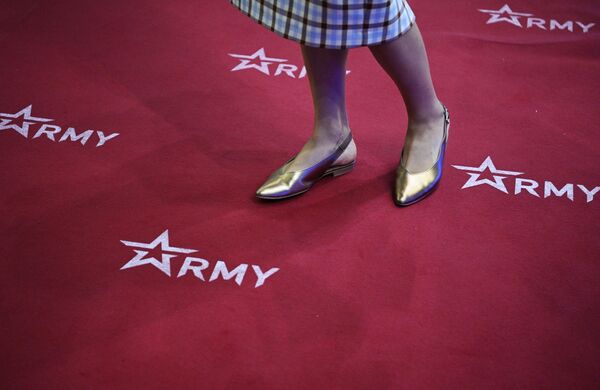 Une jeune femme sur un tapis avec les symboles du forum militaro-technique international Armée-2022. - Sputnik Afrique