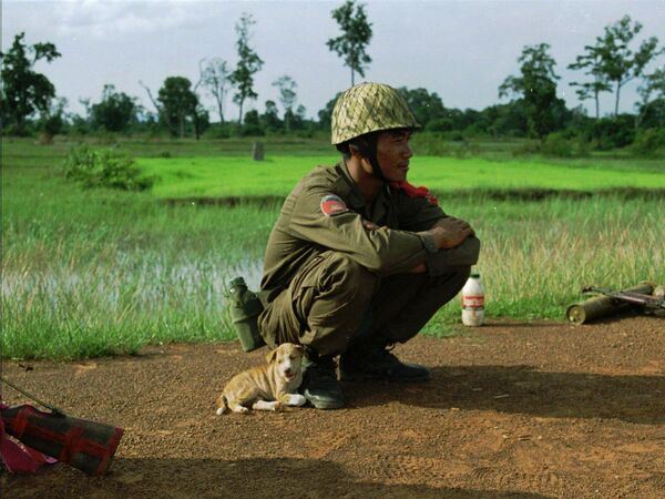 Un soldat du gouvernement se lie d&#x27;amitié avec un chiot errant avant de se battre contre des résistants fidèles au co-Premier ministre déchu du Cambodge, le prince Norodom Ranariddh, le 9 août 1997 près de Khtum, non loin de la frontière avec la Thaïlande. Peu de temps après avoir joué avec le petit chien, le soldat a été blessé à la jambe par un tir d’AK-47. - Sputnik Afrique