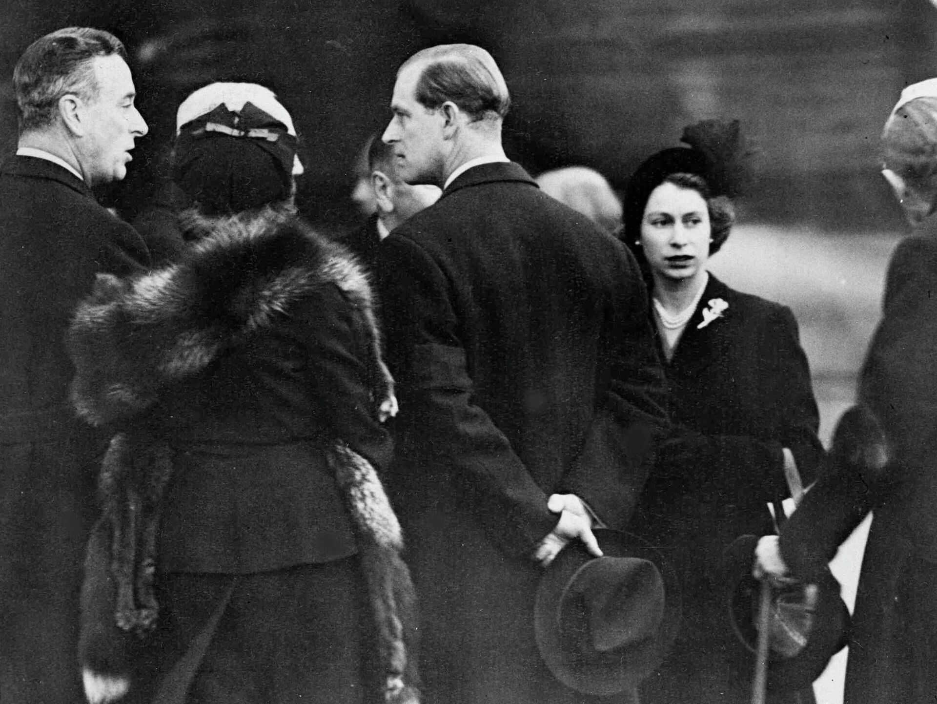 Britain's Queen Elizabeth II, right, and her husband Prince Philip, the Duke of Edinburgh, centre with back to camera, are greeted on their arrival at London Airport, on Feb. 7, 1952. The royal couple cut short their official trip to Kenya and returned home following the death of King George VI. Prince Philip is talking to Earl Louis Mountbatten of Burma, left. - Sputnik Afrique, 1920, 10.09.2022