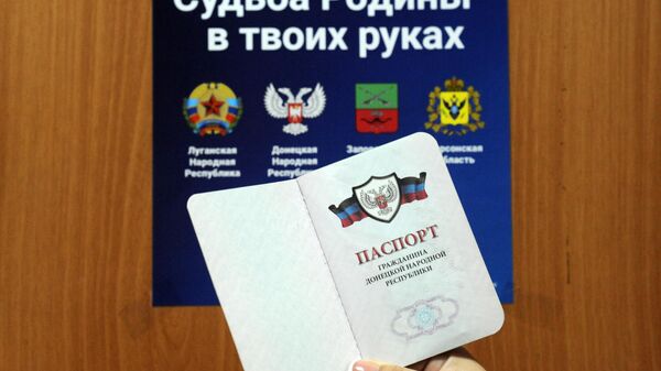 Une citoyenne de la République populaire de Donetsk tient son passeport sur fond de pancarte sur les référendums, septembre 2022 - Sputnik Afrique