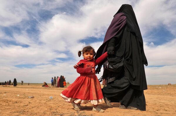 Une femme entièrement voilée marche avec sa fille alors que des civils fuyant des terroristes se rassemblent dans la province syrienne orientale de Deir ez-Zor. - Sputnik Afrique