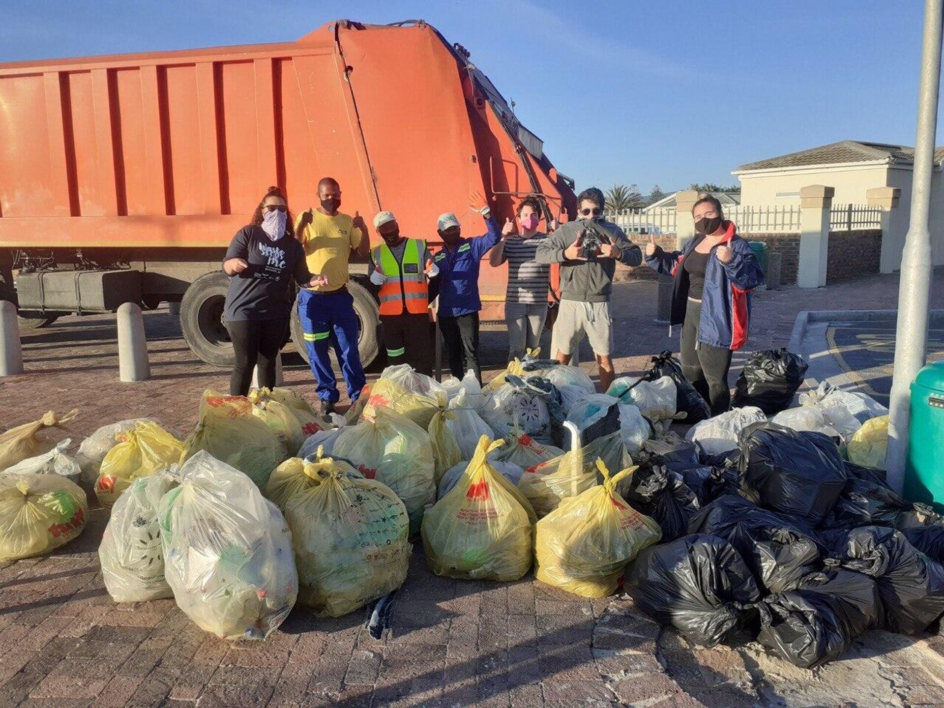 Zoe Prinsloo, the founder and CEO of Save a Fishie, and other eco-activists behind garbage they collected during a beach clean-up in South Africa - Sputnik Africa, 1920, 30.03.2023