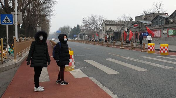 Women in medical masks cross the street in Beijing. - Sputnik Africa