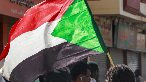 A man waves a Sudanese national flag while taking part in a protest march against a deal agreed the previous month between military leaders and some civilian factions on a two-phase political process since the 2021 military coup, headed towards the presidential palace in Sudan's capital Khartoum on January 24, 2023. - Sputnik Africa