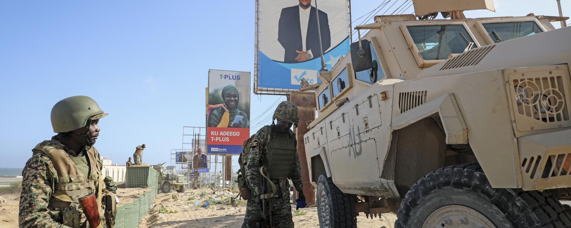 Ugandan peacekeepers with the African Transition Mission in Somalia (ATMIS) stand next to their armored vehicle, with a campaign poster for presidential candidate Ahmed Abdullahi Samow seen above, on a street in Mogadishu, Somalia Tuesday, May 10, 2022 - Sputnik Africa, 1920, 03.04.2023
