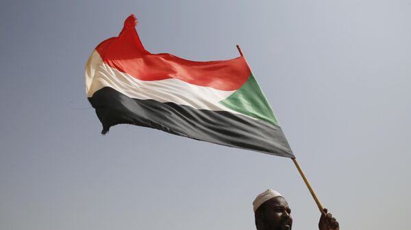 A Sudanese supporter of Gen. Mohammed Hamdan Dagalo, the deputy head of the military council, holds a national flag during a military-backed tribe's rally, in the East Nile province, Sudan, Saturday, June 22, 2019.  - Sputnik Africa