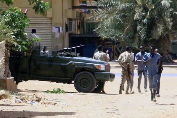 People run past a military vehicle in Sudan&#x27;s capital city on April 15, 2023. - Sputnik Africa