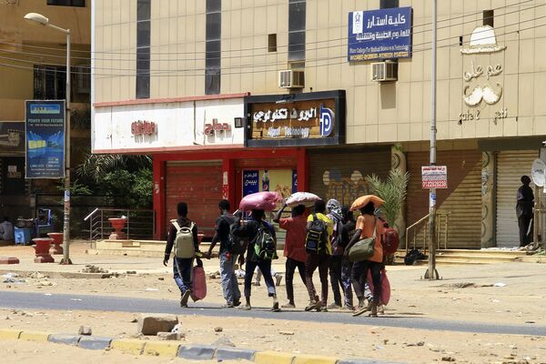 People carrying their belongings walk along a street in Sudan&#x27;s capital. - Sputnik Africa