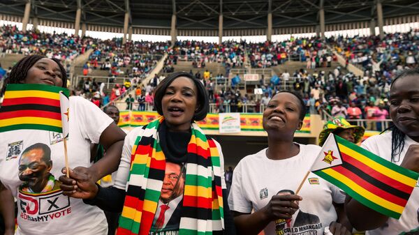 Supporters of President Emmerson Mnangagwa wave flags during the celebration of Zimbabwe's 39th Independence Day anniversary at the country's National Sports Stadium on April 18, 2019 - Sputnik Africa