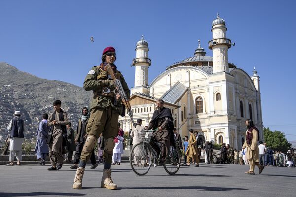 A Taliban fighter stands guard as Afghan people attend Eid al-Fitr prayers, marking the end of the holy fasting month of Ramadan, in Kabul, Afghanistan. - Sputnik Africa