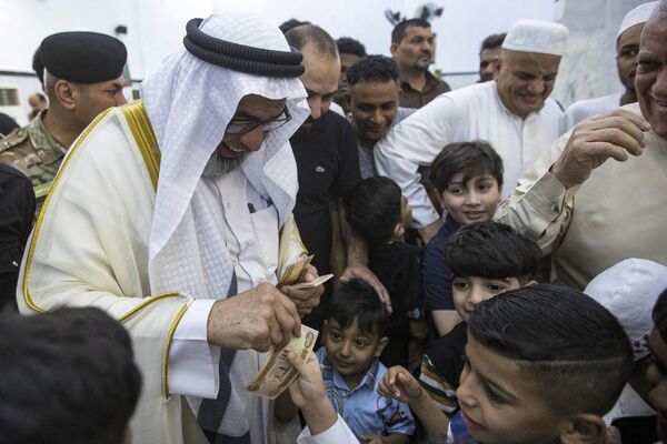 Sheikh Mohamed al-Mulla, head of the Basra Sunni Waqf (endowment), hands out money to children as Sunni Muslims celebrate on the first day of Eid al-Fitr at the Grand Mosque in Basra. - Sputnik Africa