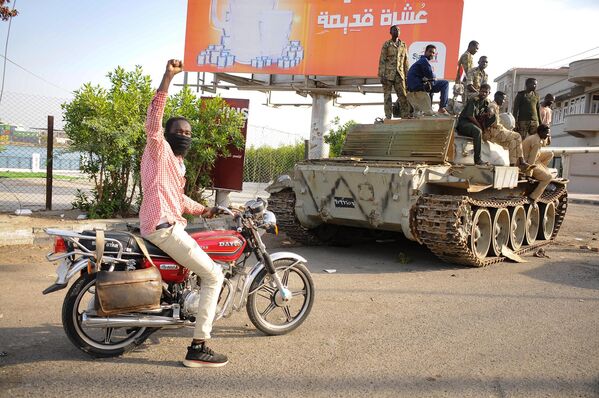 A man raises his arm in support as he drives near Sudanese army soldiers loyal to army chief Abdel Fattah al-Burhan, manning a position in the Red Sea city of Port Sudan, on April 20, 2023. - More than 300 people have been killed since the fighting erupted April 15 between forces loyal to al-Burhan and his deputy, Mohamed Hamdan Daglo, who commands the paramilitary Rapid Support Forces (RSF) - Sputnik Africa