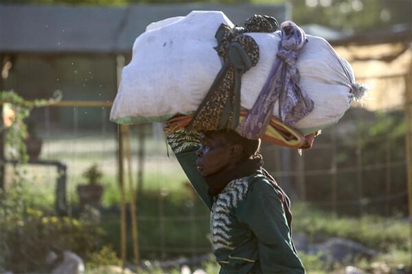 A woman carries her belongings as she flees amid fighting between the army and paramilitaries in Khartoum on April 19, 2023, following the collapse of a 24-hour truce.  - Sputnik Africa