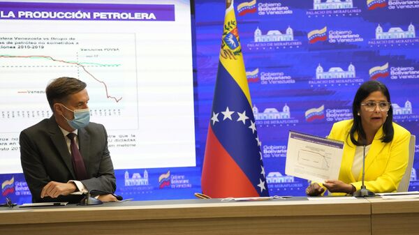 Venezuela Foreign Minister Félix Plasencia, left, listens to Venezuelan Vice President Delcy Rodriguez, right, as she holds a graphic where it shows the drop in Venezuela´s oil production, during a press conference, at Miraflores Presidential Palace in Caracas, Venezuela, Tuesday, Aug. 24, 2021.  - Sputnik Africa