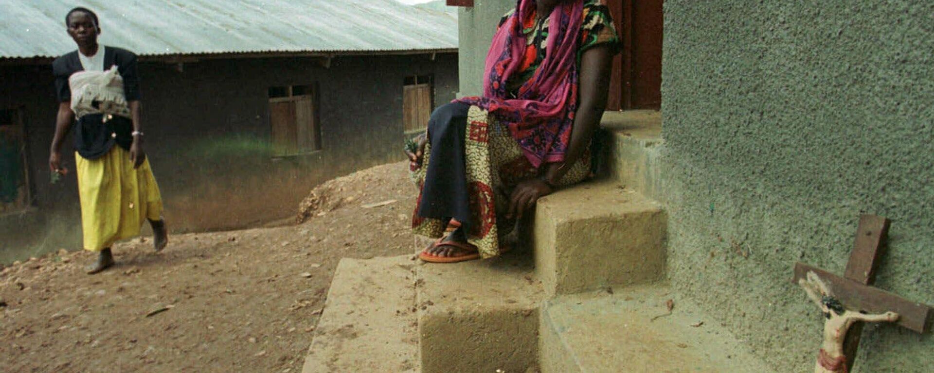 Sitting on the steps of the church, a Kanungu villager looks at a crucifix which was left behind by a cult member who now lays dead inside in Kanungu, southwestern Uganda Sunday, March 19, 2000, about 220 miles (350 kilometers) southwest from the capital Kampala, where members of a doomsday cult died in a fire. - Sputnik Africa, 1920, 06.03.2023